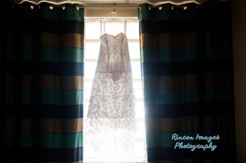 White wedding dress with beautiful beading hanging in a window. Photographed by Rincon Images wedding photographer Rincon Puerto Rico.
